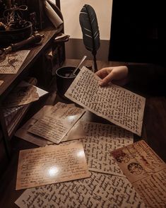 several old books are spread out on a table with an ink pen and quill