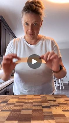 a woman standing in front of a kitchen counter holding a wooden spoon over a cutting board