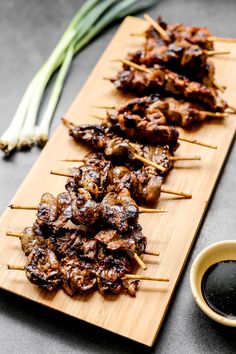 several skewered meats are sitting on a wooden board