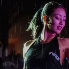 a woman standing in the rain with her headphones on and ear phones up to her ear