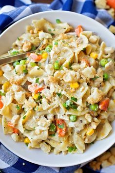 a bowl filled with pasta and vegetables on top of a blue and white table cloth