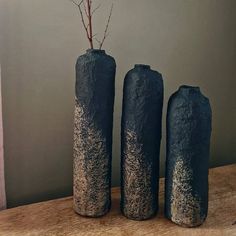 three black vases sitting on top of a wooden table