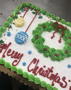 a cake decorated with green frosting and red writing that says happy christmas on it