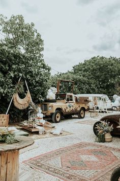 an old truck is parked in the middle of a yard with other antique cars and furniture