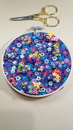 a pair of scissors sitting on top of a blue and purple flowered circular coaster