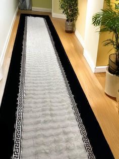 a long black and white rug on the floor next to a plant in a room