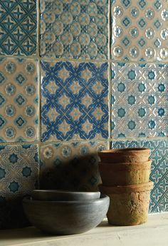 three bowls sitting next to each other in front of a wall with blue and white tiles