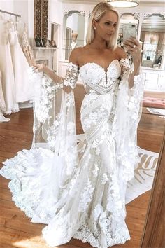 a woman taking a selfie in a wedding dress with her hand on her hip