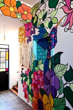 an artisticly painted wall with flowers and leaves on the outside, in front of a doorway