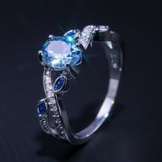 an engagement ring with blue and white stones on the side, set against a black background