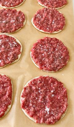 raw hamburger patties sitting on top of a cookie sheet ready to go into the oven