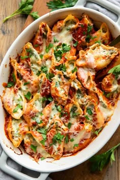 a casserole dish with chicken, spinach and tomato sauce in it on a wooden table