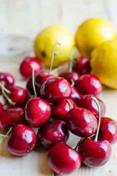 some cherries and lemons on a wooden table