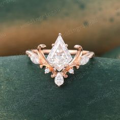 an engagement ring with a pear shaped diamond surrounded by smaller pear shaped diamonds on top