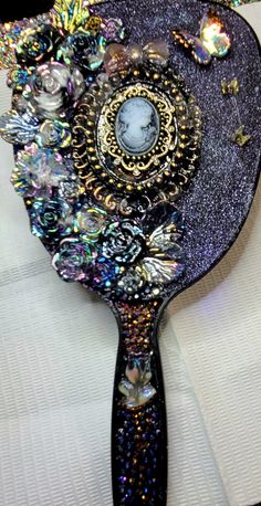 a close up of a hair brush on a white cloth with sequins and jewels