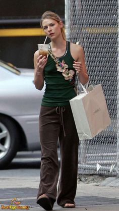 a woman walking down the street while holding shopping bags and looking at her cell phone