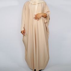 Drape yourself in our new line of luxurious open abayas. Their batwing design and open style allows the fabric to drape beautifully and create movement. The fabric is textured with a slight and subtle sheen when steamed. The solid colours and the classic cut make this abaya a classic staple that is a must have in your wardrobe. Perfect for those who don't want the distractions of a busy design. The wide sleeves with the small split gives it that contemporary touch. Included are a matching slip and hijab. Available in various colours, please check the store.   Available in Sizes: 50, 52, 54, 56, *58 and 60. Please choose your size from the drop down menu. *Please note 58 has slight machine defects and the price does reflect this.  Here at Pixie Plum we're proud to bring you a collection of Solid Long Thobe For Eid, Long Thobe For Eid, Beige Long Thobe For Eid, Modest Long Solid Color Kaftan, Floor-length Beige Abaya For Eid, Long Modest Abaya With Dabka, Modern Abaya Dubai, Open Abayas, Eid Abaya