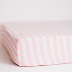 a pink and white striped bed sheet on top of a white table with a black object in the corner