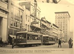 an old black and white photo of two trolleys on the street in front of tall buildings