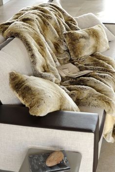 a white couch with a brown and black blanket on top of it next to a table