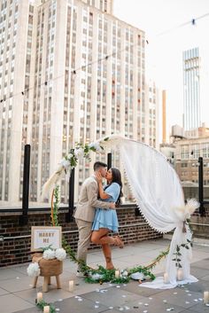 a man and woman kissing in front of a wedding arch