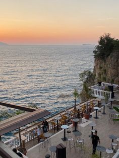 people are sitting at tables near the ocean