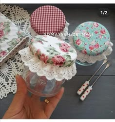 a hand holding a small cake with flowers on it and lace doily around it