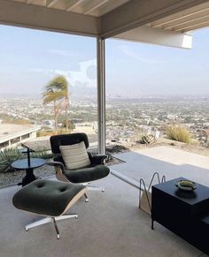 a living room filled with furniture and a large window overlooking the cityscape in the distance