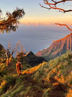 a man hiking up a hill with the ocean in the background