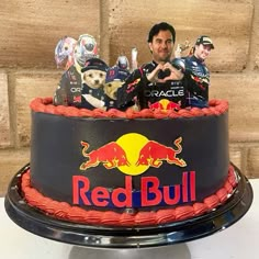 a red bull cake is decorated with figurines on top and an image of the driver