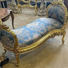 an ornate gold and blue bench in a room with other antique furniture, including tables