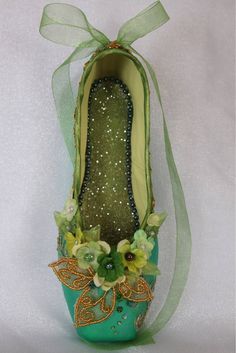 a pair of green shoes with flowers on the bottom and gold sequins around the toes