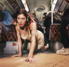 a woman is laying on the floor in an empty train car with people standing around her