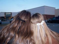 two women with braids on their hair standing in front of a building