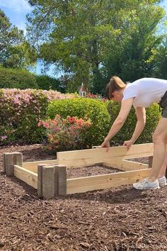 a woman bending over to build a garden bed