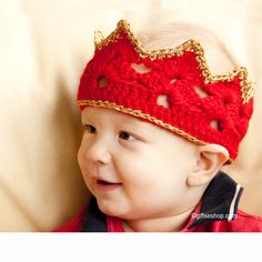 a baby wearing a red crocheted crown hat