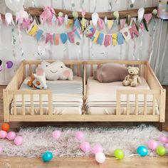 a baby's room with two cribs and balloons hanging from the ceiling