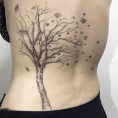 a woman's back with a tree tattoo on it