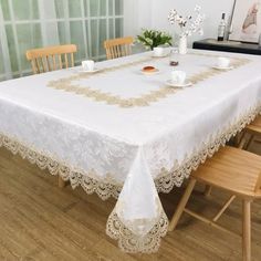 a white table cloth with gold trimmings and lace on it in front of a window