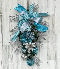 a blue and silver christmas wreath on a white wooden floor with snowflakes, ornaments and ribbons