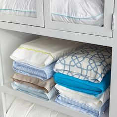 a white cabinet filled with lots of pillows and blankets