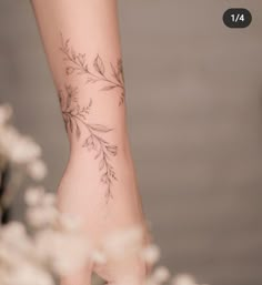 a woman's foot with tattoos on it and flowers in the foreground behind her