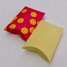 two pieces of yellow paper with red and yellow emoticions on them, one is folded to the side