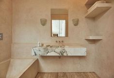 a bathroom with a marble sink and shelves on the wall, along with wooden flooring