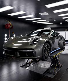 a car being worked on in a garage with lights above and below the cars wheels