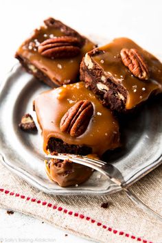 two pieces of chocolate pecan brownies on a plate with a fork