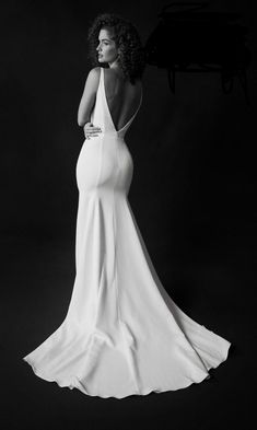 a woman in a white dress standing next to a piano