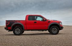 a red truck parked on top of a dirt field