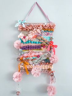 a wall hanging made out of yarn and pom poms