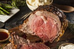 roast beef on a cutting board with sauces and asparagus